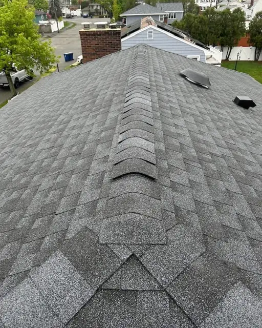 Ridge cap shingles and roof vents along the peak of a gray asphalt roof